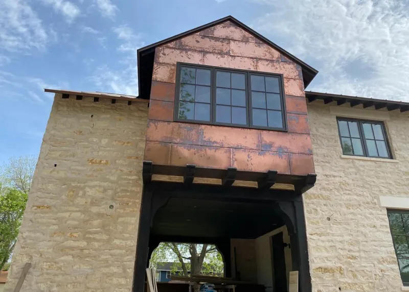 Copper metal panel facade on a stone building for Roof Repair in Lake Grove