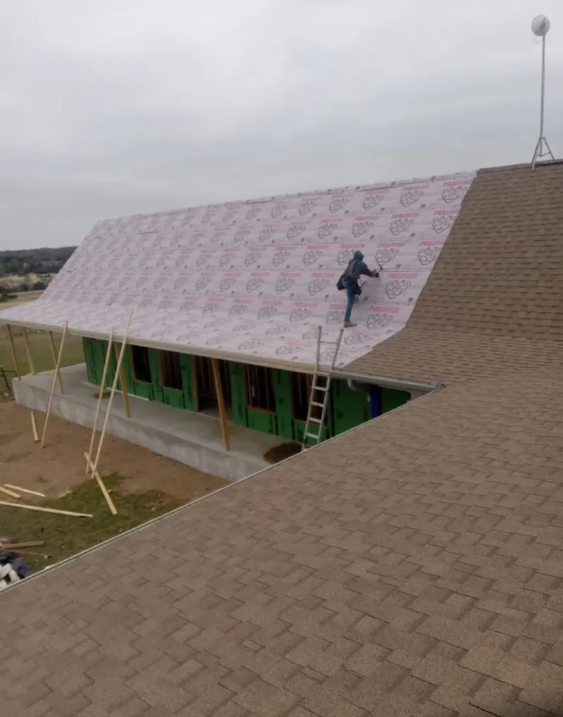 Worker preparing underlayment for a metal roof installation in Lake Grove